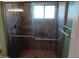 Bathroom shower with dark tile, glass doors, brushed nickel hardware, and a window for natural light at 2901 W Straford Dr, Chandler, AZ 85224