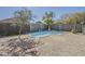 Backyard featuring a pool, gravel landscaping, trees, and a block wall at 36307 W El Greco St, Maricopa, AZ 85138