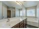 Main bathroom with double sinks, lots of cabinet storage, a large mirror, and a large tub at 36307 W El Greco St, Maricopa, AZ 85138