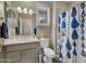 Well-lit bathroom with a shower and patterned curtain next to the toilet and a sink with shuttered window at 41310 N Clear Crossing Ct, Anthem, AZ 85086