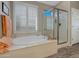 Soaking tub sits beneath shuttered window and is adjacent to a glass enclosed shower in this well-lit bathroom at 41310 N Clear Crossing Ct, Anthem, AZ 85086