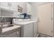 Well-lit laundry room with white washer and dryer, sink, and storage cabinets at 42207 N 45Th Dr, Phoenix, AZ 85086