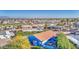 An elevated aerial view showing a blue house with a brown roof among lush greenery, with the neighborhood beyond at 654 S 83Rd Way, Mesa, AZ 85208