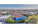 A high-angle view shows a blue home nestled in a neighborhood with mature trees under a clear blue sky at 654 S 83Rd Way, Mesa, AZ 85208