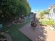 Private backyard with artificial grass, a cozy fire pit area, and mature trees offering ample shade at 654 S 83Rd Way, Mesa, AZ 85208