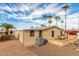 Tan single-story home with a brick patio, surrounded by gravel and lush palm trees under a partly cloudy sky at 8103 E Southern Ave # 119, Mesa, AZ 85209