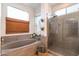 Modern bathroom showcasing a soaking tub, glass shower, and neutral tiling at 8362 W Rosewood Ln, Peoria, AZ 85383