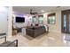 Bright living room featuring a gray sofa, ceiling fan, a large TV, and natural lighting at 8362 W Rosewood Ln, Peoria, AZ 85383