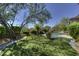 Well-manicured backyard with artificial turf, mature trees, and a sparkling pool at 9671 E Cavalry Dr, Scottsdale, AZ 85262