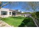 Spacious backyard featuring a manicured lawn, outdoor kitchen, fire pit, and desert landscaping at 9671 E West View Dr, Scottsdale, AZ 85255