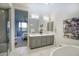 Contemporary bathroom showcasing double sinks, gray cabinets, artistic decor, and a glimpse into the main bedroom at 9671 E West View Dr, Scottsdale, AZ 85255