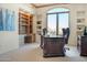 Home office with a built-in bookcase, large desk, comfortable chair, and ample natural light at 10379 E White Feather Ln, Scottsdale, AZ 85262