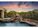 Relaxing pool area featuring a rock waterfall, lounge seating, and views of the desert landscape at 10379 E White Feather Ln, Scottsdale, AZ 85262