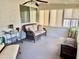 Bright sunroom with a wicker couch, neutral tones, and lots of natural light from the many windows and sliding glass door at 10414 N 105Th Ave, Sun City, AZ 85351