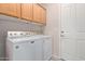 Laundry room with a white washer and dryer, wooden cabinets and door to the outside at 11034 E Natal Ave, Mesa, AZ 85209