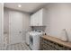 Functional laundry room equipped with appliances, upper cabinets, and decorative tile flooring at 11172 N San Clemente St, Surprise, AZ 85388