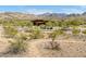 A modern home with an American flag and desert landscaping is nestled in the mountains at 11182 S Hopi Dr, Goodyear, AZ 85338