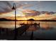 Picturesque lake view featuring a silhouette of a dock and vibrant sunset colors in the sky at 11182 S Hopi Dr, Goodyear, AZ 85338