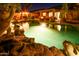 Backyard pool at night with lush tropical landscaping and a cozy fire pit under the covered patio at 11182 S Hopi Dr, Goodyear, AZ 85338