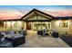 The rear of the home has an expansive patio area with elegant outdoor seating beneath a gabled roof extension at 12201 N 65Th St, Scottsdale, AZ 85254