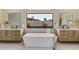 Bright bathroom featuring a soaking tub, double vanity, and a large window overlooking the yard at 12201 N 65Th St, Scottsdale, AZ 85254