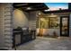 A covered outdoor kitchen featuring a built-in BBQ, drawers, and stone accent wall on a stone-paved patio at 12201 N 65Th St, Scottsdale, AZ 85254