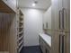 Bright walk-in closet featuring custom shelving and ample storage space with modern gray finishes and black tile floors at 12201 N 65Th St, Scottsdale, AZ 85254
