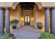 Inviting entryway with arched double doors, brick flooring, pillars, potted plants, and warm lighting at 14675 E Paradise Dr, Fountain Hills, AZ 85268