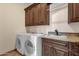 Well-equipped laundry room featuring matching washer and dryer, custom cabinetry, and utility sink at 14675 E Paradise Dr, Fountain Hills, AZ 85268