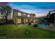 An evening view of the backyard with a sparkling pool, well-maintained lawn, and covered patio at 16018 N 17Th Way, Phoenix, AZ 85022