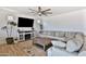 Bright and airy living room featuring a large sofa, ceiling fan, wood-look flooring, and a modern TV console at 16873 W Fetlock Trl, Surprise, AZ 85387