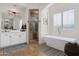 Bright bathroom with a soaking tub, walk-in shower, and double vanity with stylish black and white rug at 17302 N 99Th Pl, Scottsdale, AZ 85255