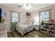 Cozy bedroom with pink walls, decorative curtains, and wood-look flooring at 18039 W Sunnyslope Ln, Waddell, AZ 85355