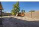 Wide shot of the backyard featuring a large tree, dirt, and paved walkway at 18194 N 59Th Ln, Glendale, AZ 85308