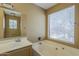 Bright bathroom with a tub, a shower, and a large window at 18194 N 59Th Ln, Glendale, AZ 85308