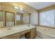 Bathroom with a double sink vanity and a large tub, and a bright window at 18194 N 59Th Ln, Glendale, AZ 85308
