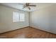 A simply staged bedroom features wood floors, a ceiling fan, and a window with blinds at 18194 N 59Th Ln, Glendale, AZ 85308