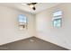 This bedroom has neutral carpet, a ceiling fan and two windows at 19685 W Roma Ave, Litchfield Park, AZ 85340