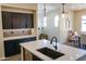 Bright kitchen featuring an island with a sink, dark cabinets, and modern pendant lighting at 250 W Queen Creek Rd # 229, Chandler, AZ 85248