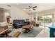 Comfortable living room with a leather sofa, ceiling fan, and a sliding glass door to the backyard at 26242 S Thistle Ln, Sun Lakes, AZ 85248