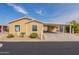 Inviting single-story home with covered carport, lush landscaping, and painted in light yellow at 40569 N Wedge Dr, San Tan Valley, AZ 85140