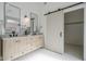 Bright bathroom with double sink vanity, modern mirrors, stylish lighting, and a sliding barn door to the closet at 40724 N Capital Ct, Anthem, AZ 85086