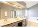 Bright bathroom with double sinks, large mirror, soaking tub, and glass-enclosed shower at 750 S Cholla St, Gilbert, AZ 85233