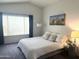 Comfortable bedroom featuring a large window with blinds, a queen bed with decorative pillows, and neutral colors at 750 S Cholla St, Gilbert, AZ 85233