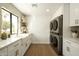 Bright laundry room features a farmhouse sink, gold fixtures, wood floors, stacked washer dryer at 9900 N 52Nd St, Paradise Valley, AZ 85253