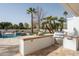 Inviting outdoor kitchen with a built-in grill, bar seating, and a view of the sparkling pool and lush landscaping at 9900 N 52Nd St, Paradise Valley, AZ 85253