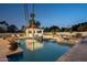 Tranquil backyard pool area with a tiled spa and covered cabana, softly lit at dusk at 9900 N 52Nd St, Paradise Valley, AZ 85253