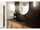 Modern powder room featuring stylish light fixtures and black marble accent wall at 9900 N 52Nd St, Paradise Valley, AZ 85253