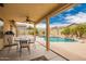 Relaxing backyard featuring a covered patio, in-ground pool with rock waterfall feature, and lush landscaping at 11318 S Hopi Dr, Goodyear, AZ 85338