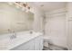 This bathroom features a double sink vanity, wood-look floors, and a shower over tub with a white tile surround at 11318 S Hopi Dr, Goodyear, AZ 85338